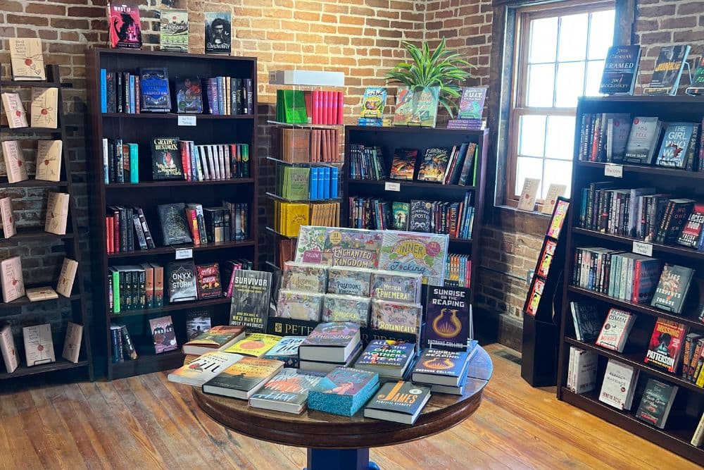 A cozy bookstore with wooden shelves filled with colorful books and a central display table showcasing featured titles.