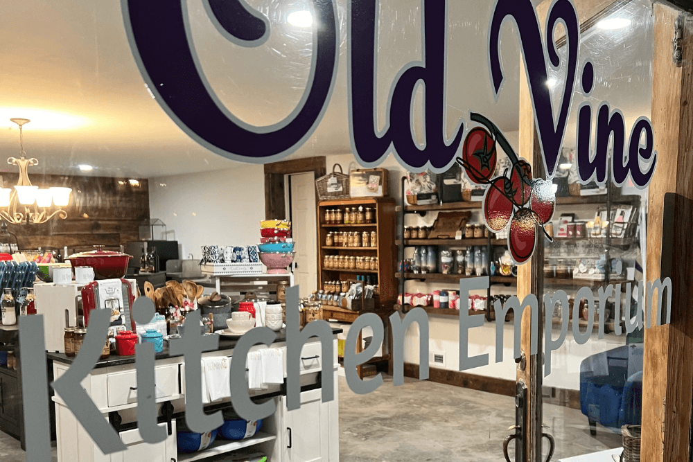 A window displays the sign for "Old Vine Kitchen Emporium," with a view of kitchenware and shelves inside.