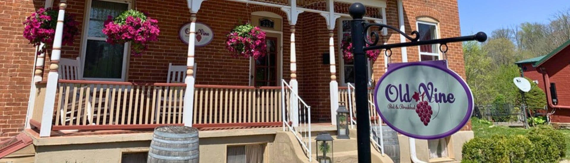 Charming brick bed and breakfast with hanging flowers and a welcoming sign.