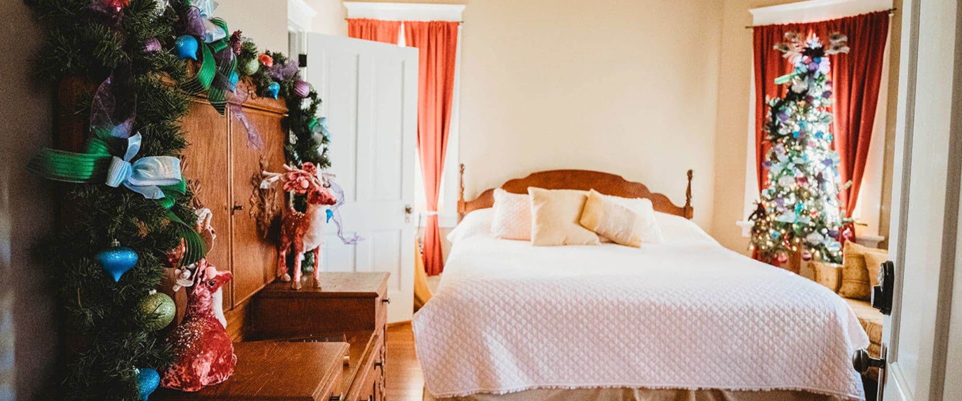 A cozy, festively decorated bedroom featuring a Christmas tree and holiday garlands.